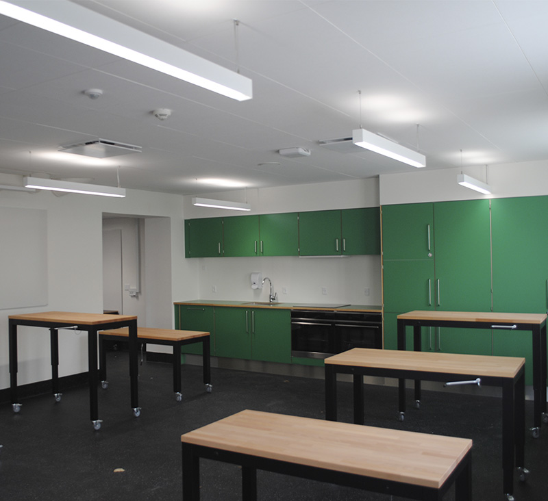 Classroom with Ropox height-adjustable tables on castors and green kitchen units