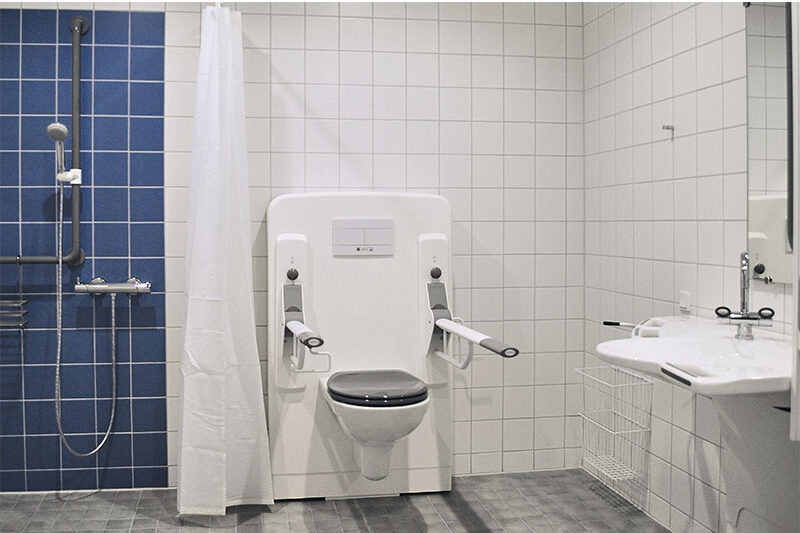 Accessible bathroom with Ropox toilet support rails, shower area and washbasin