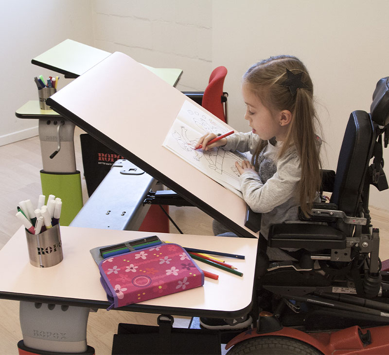 Maise drawing at her ROPOX Vision table with tilted tabletop from her wheelchair